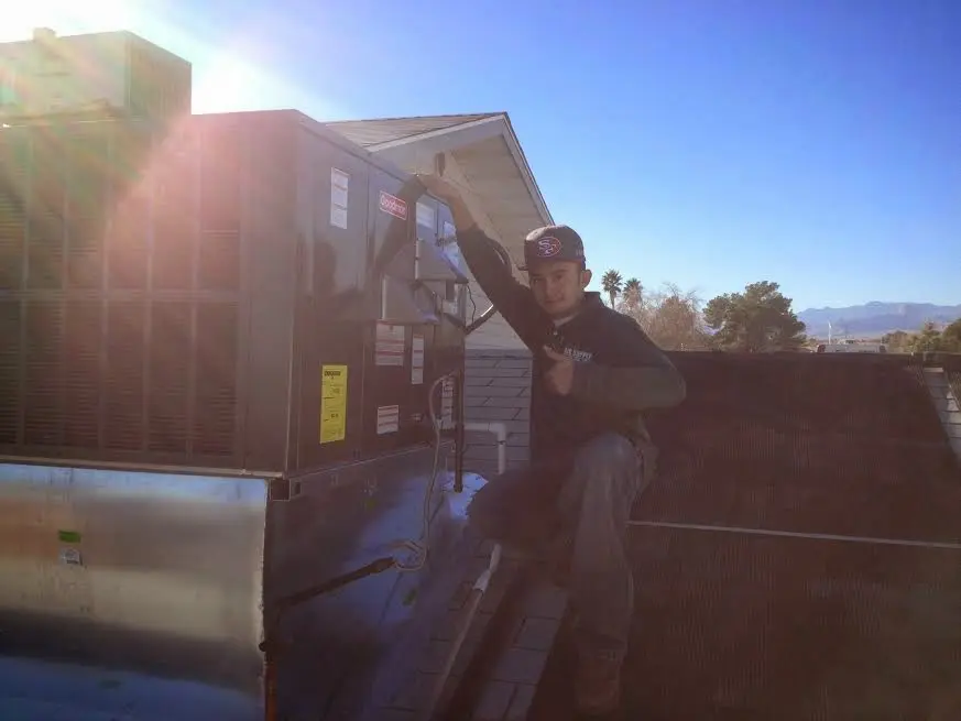 HVAC technician performing AC Tune-Up on a rooftop unit in Waggaman