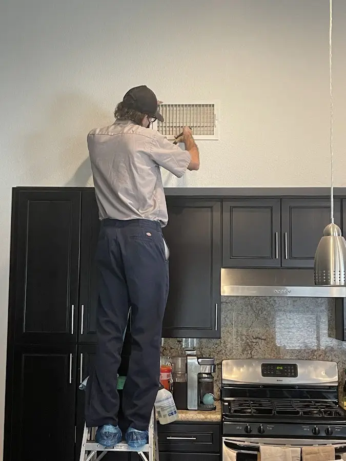 Technician inspecting an air vent during HVAC service in Waggaman